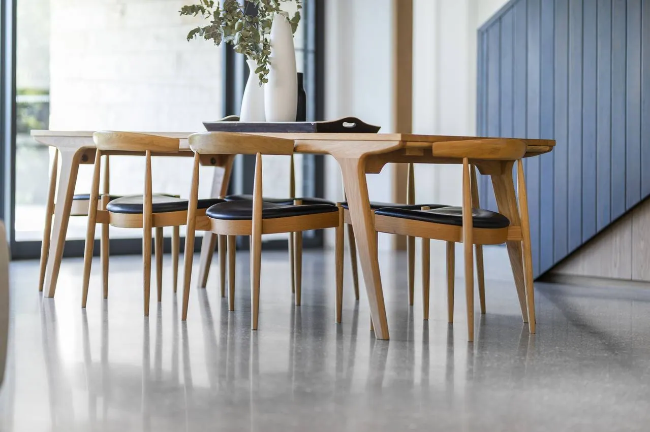 Indoor polished concrete dining-area floor with timber chairs in a modern Brisbane home