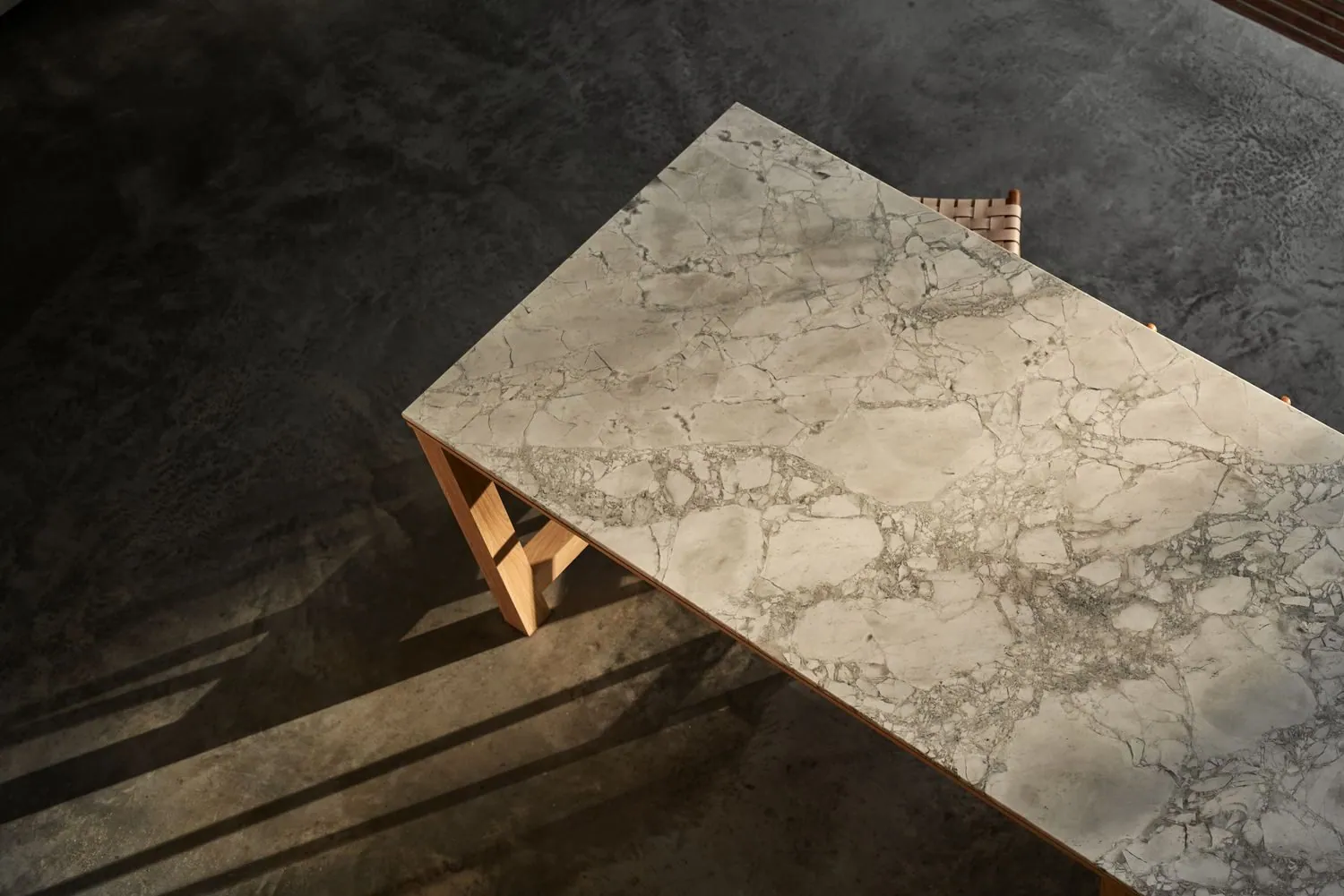 Stone dining table casting shadows across a dark polished concrete floor