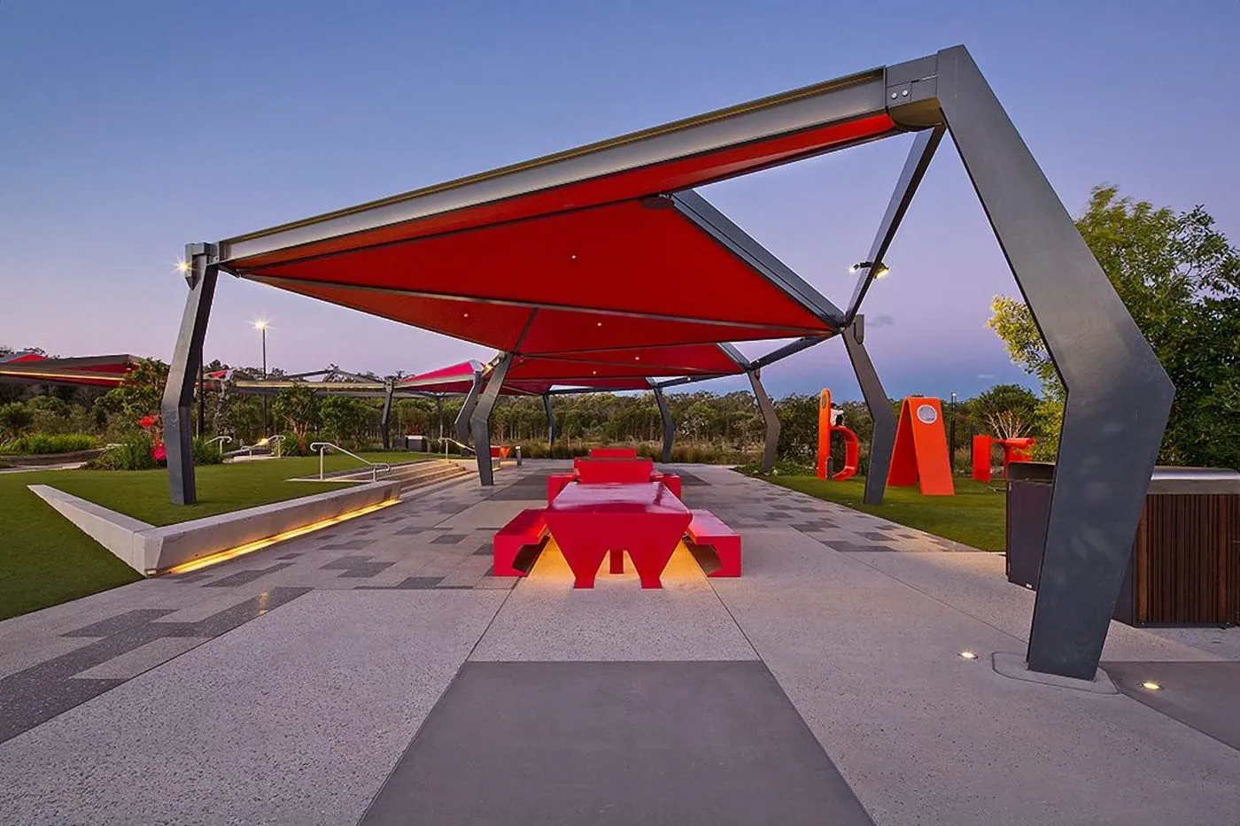 Honed concrete parkland plaza under shade structures at dusk, Baringa Town Centre on the Sunshine Coast