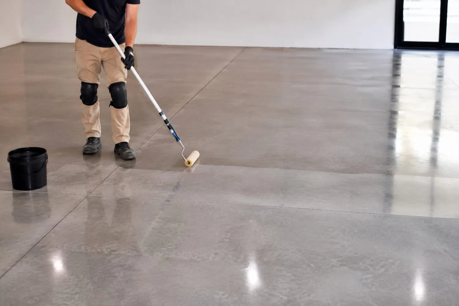 Tradesman applying sealer to a polished concrete floor in Brisbane, by OzGrind