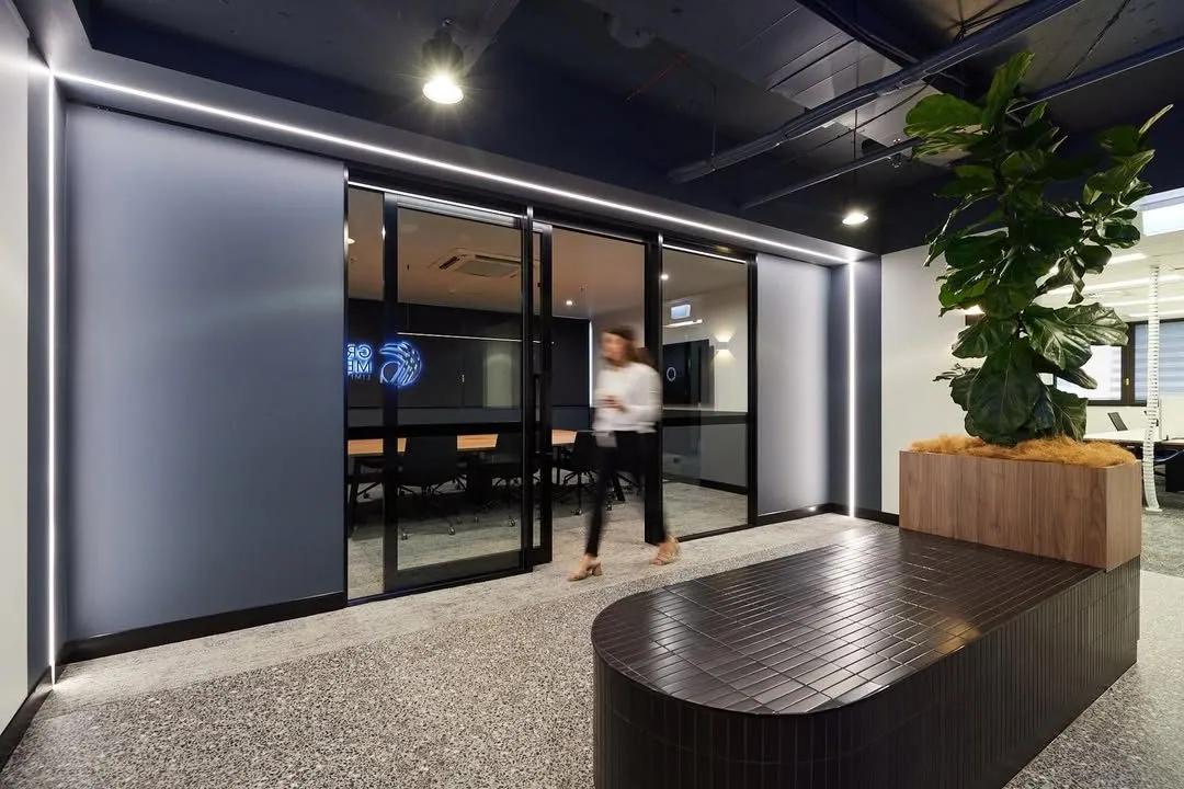 Grind and seal polished concrete floor in the reception with a tiled feature desk, neon signage and glass meeting room at the Archway commercial office fit-out, Brisbane
