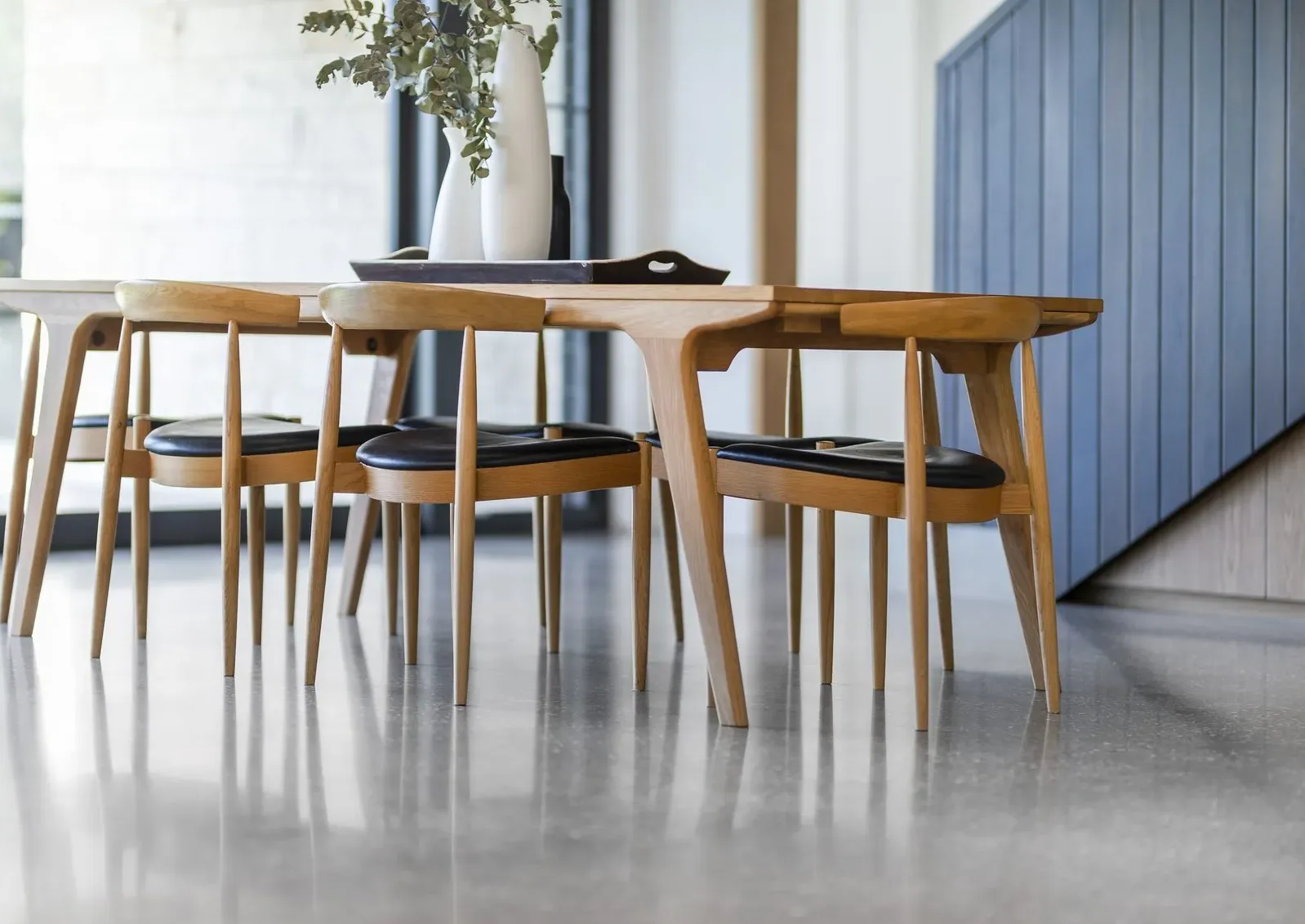 Dining table and chairs on a polished concrete floor at Hawthorne House