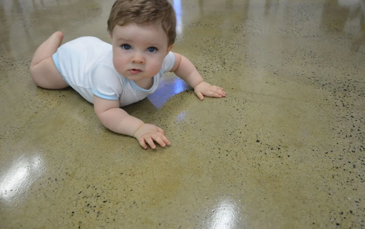 Baby crawling on a clean, sealed grind and seal polished concrete floor in a Brisbane home