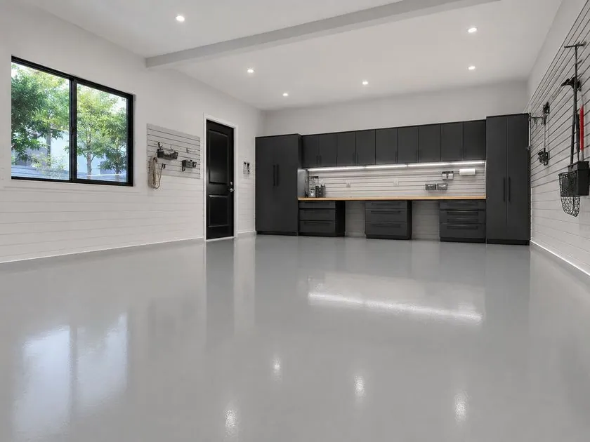 Solid colour epoxy garage floor Light grey solid colour epoxy garage floor with black storage cabinets and white shiplap walls