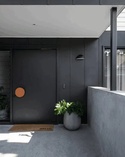 Burnished concrete entry floor at a dark-clad Brisbane home