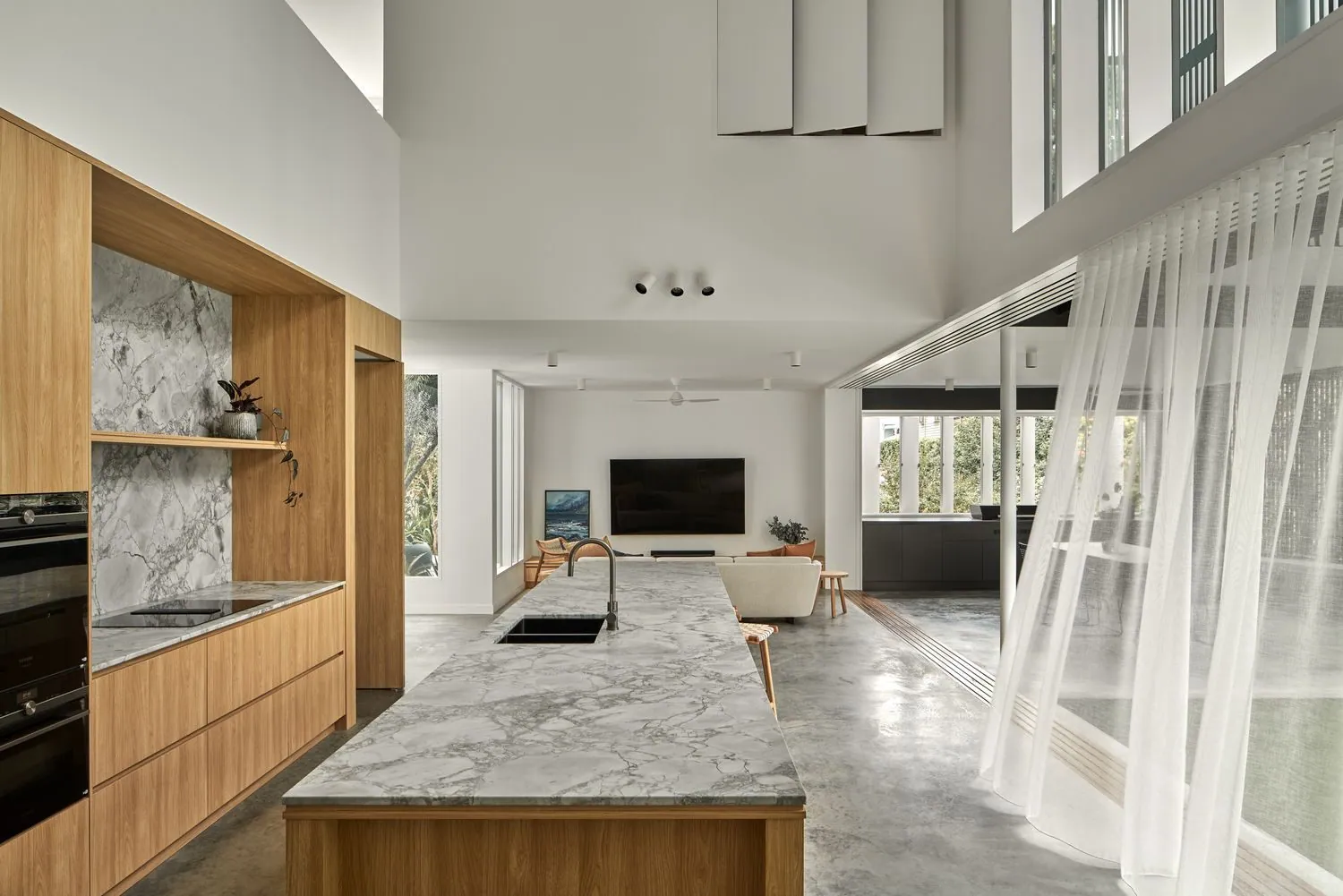 Kitchen and living area with a light honed concrete floor and stone island