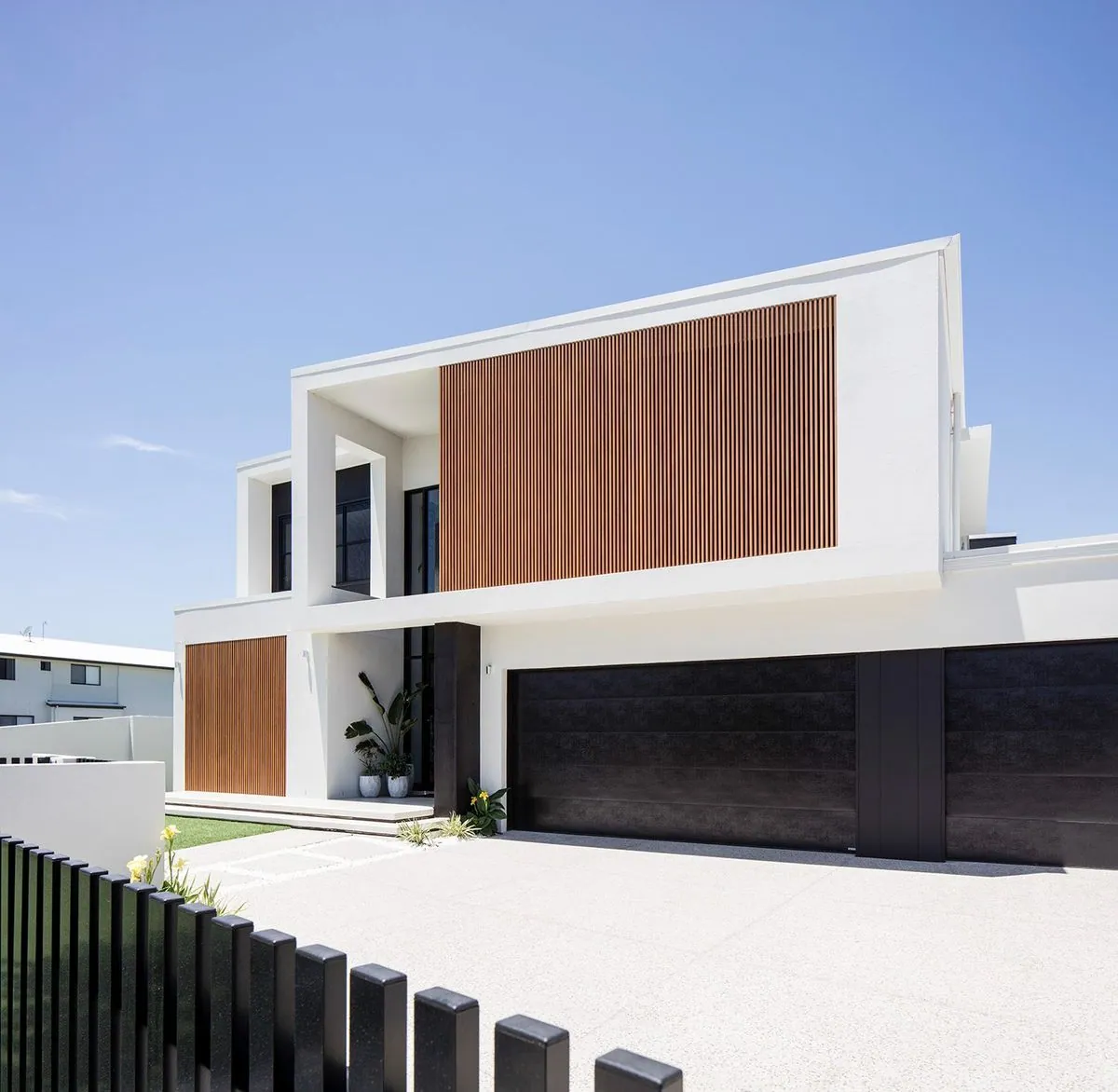Modern Brisbane home with a light honed concrete driveway by OzGrind