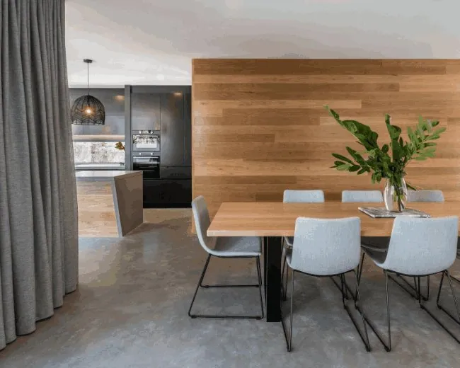 Burnished concrete dining floor with a timber feature wall in Brisbane