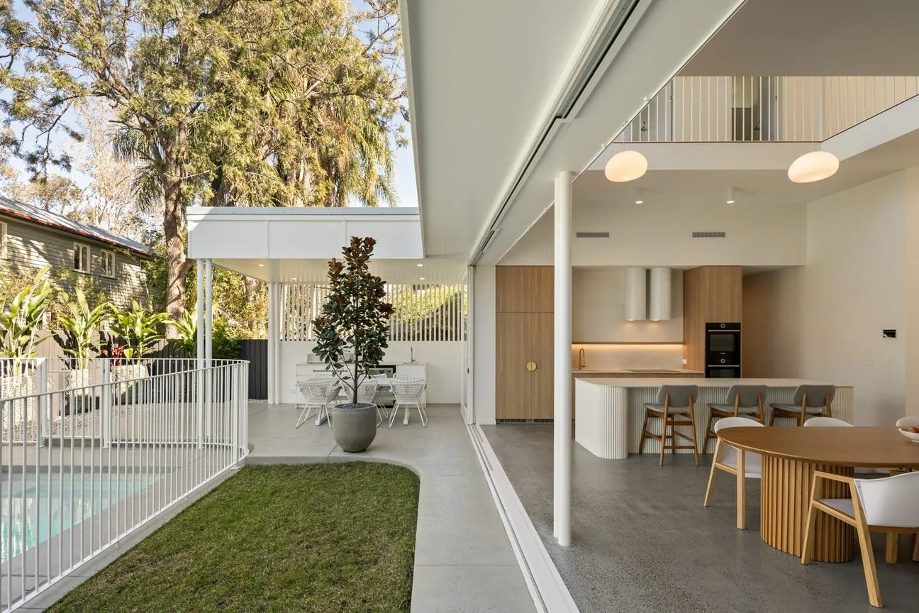 Indoor-outdoor living and dining opening to a pool and lawn with honed concrete floors in Brisbane