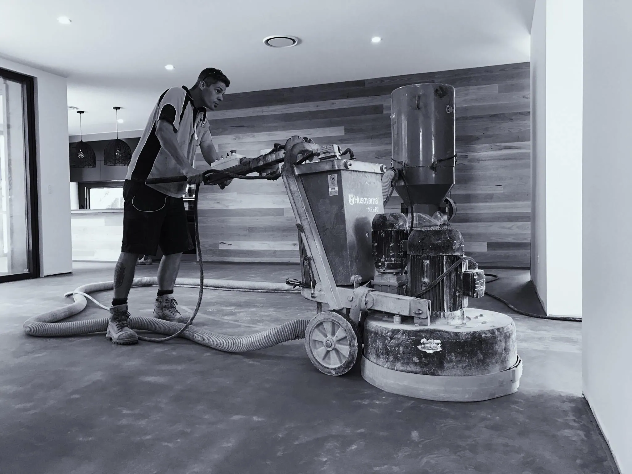 OzGrind technician grinding a concrete floor with a dustless Husqvarna grinder inside a Queensland home