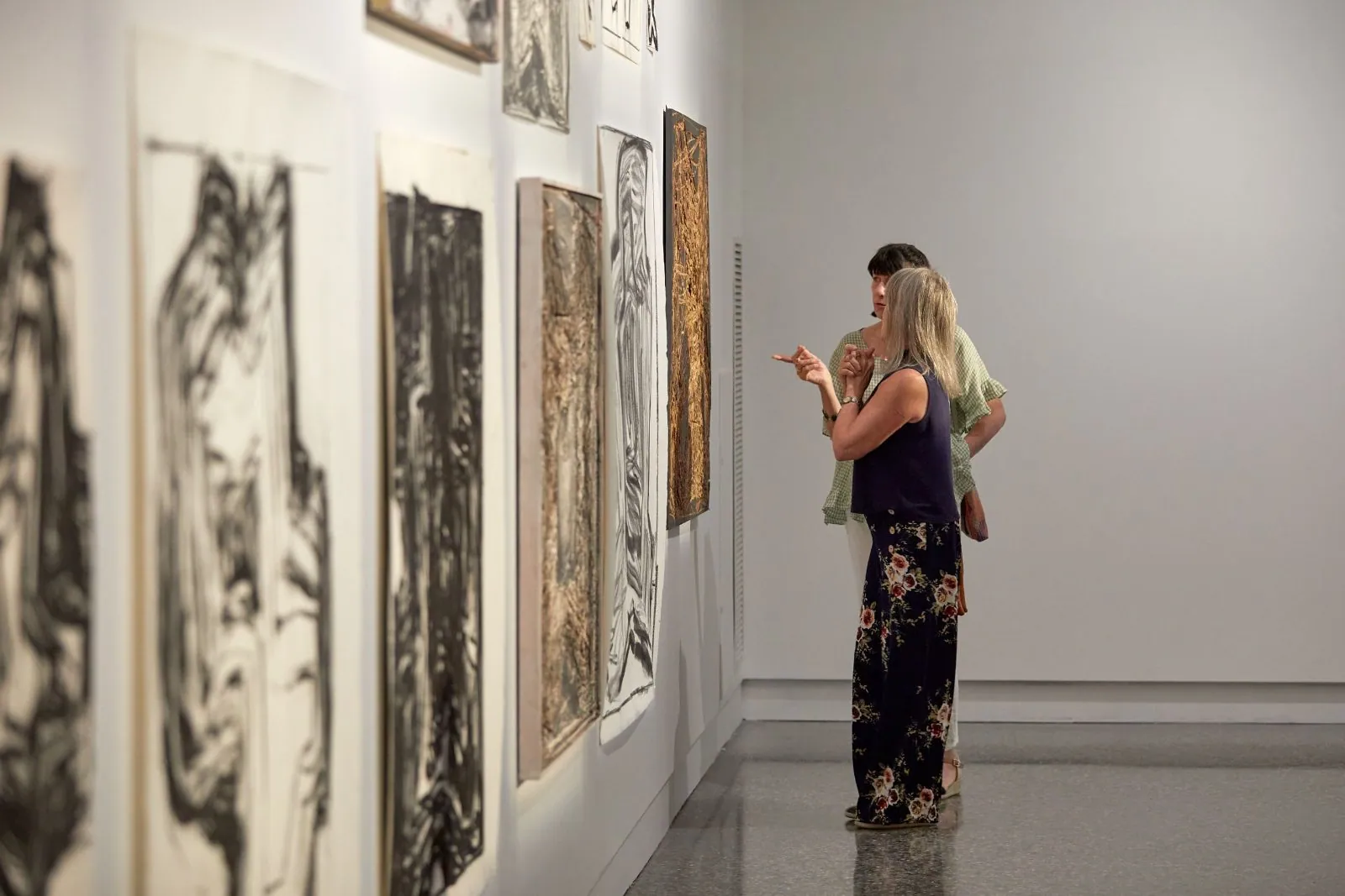 Visitor viewing large charcoal works above a polished concrete floor at Murray Art Museum Albury