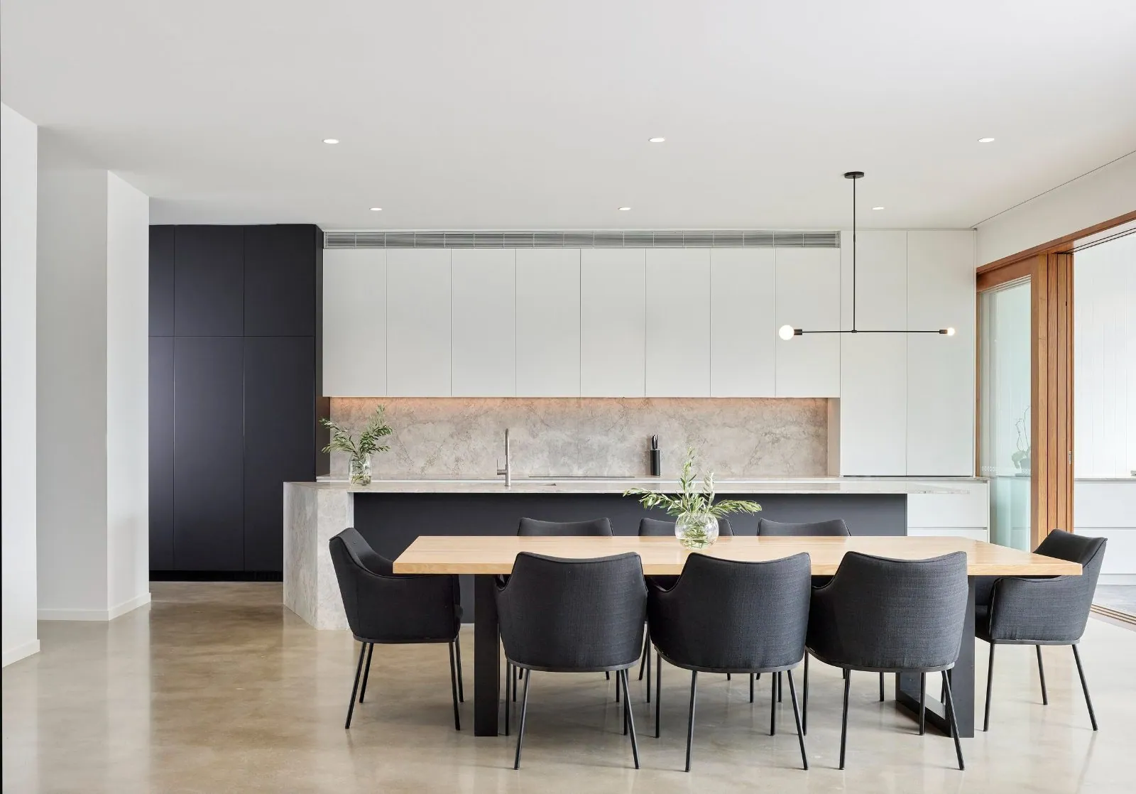 Open-plan kitchen and dining with a natural matte cement-finish concrete floor in a Brisbane home