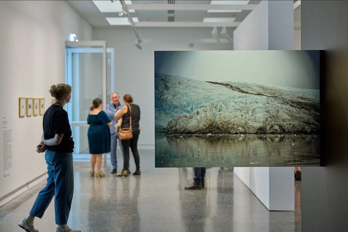 Visitors viewing a glacier photograph in a polished concrete floored gallery at Murray Art Museum Albury