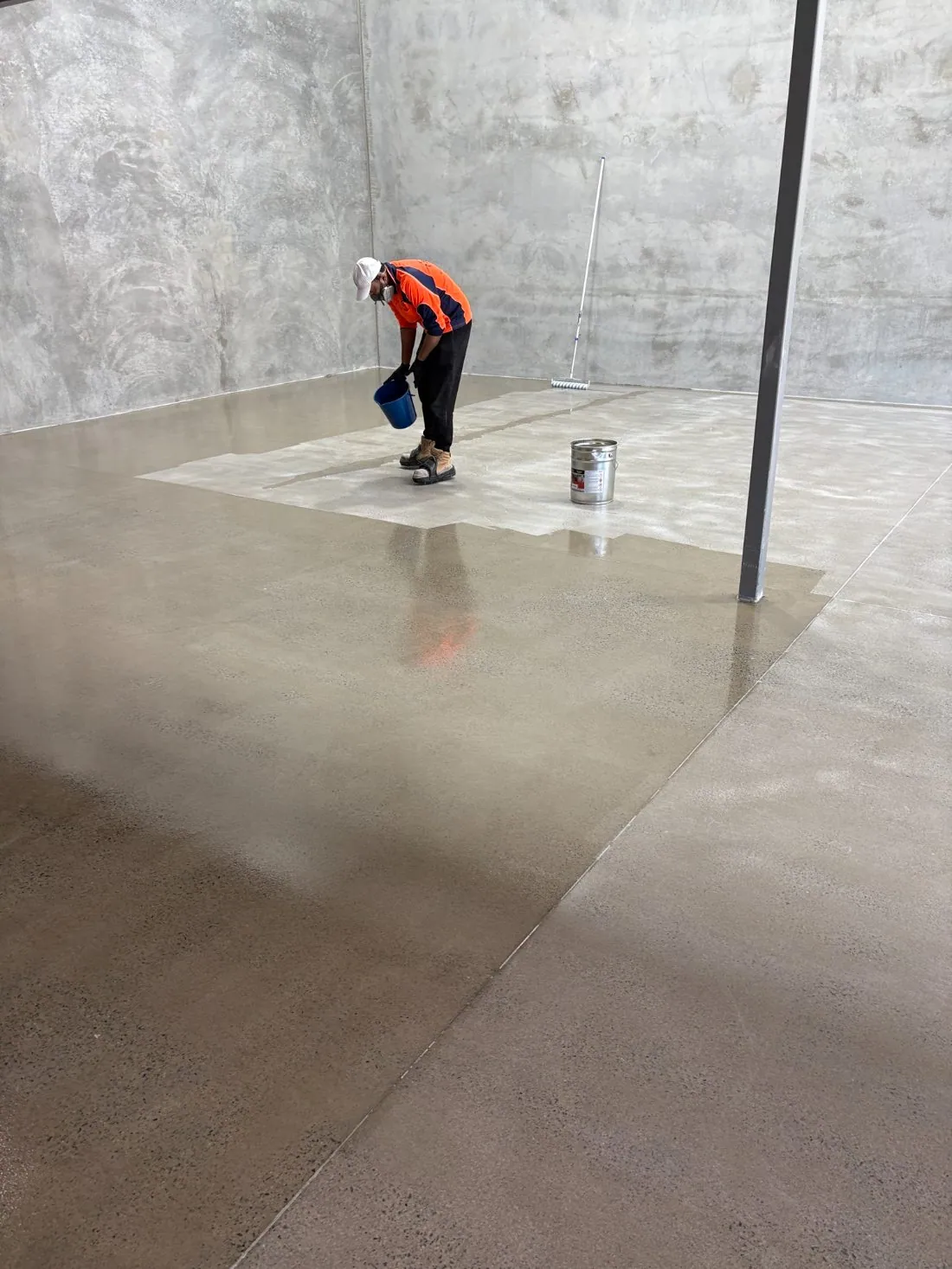 Tradesman applying sealer to a concrete floor in a Brisbane industrial unit