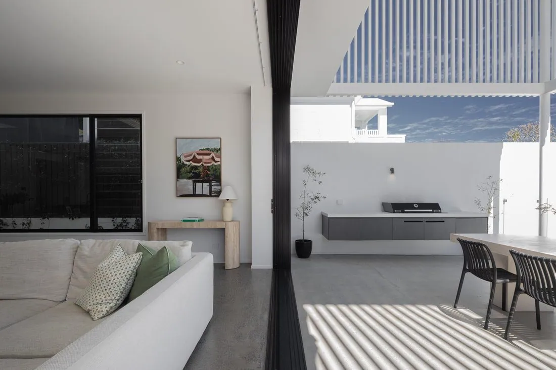 Living area opening to the alfresco with honed concrete underfoot at the Eclat Building home, Hendra