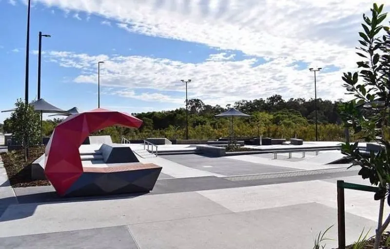 Honed concrete path beside a shade sail playground in the Stockland Aura parkland, Baringa