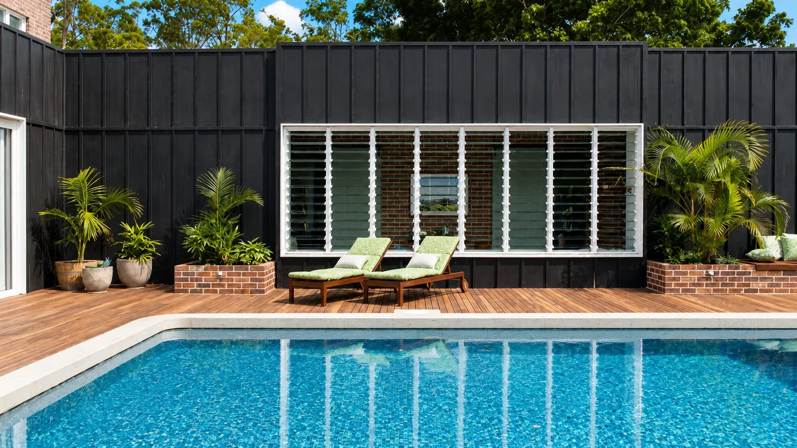 Honed concrete pool surround with timber deck, sun loungers and tiled pool, featured on Ready Set Reno, Brisbane