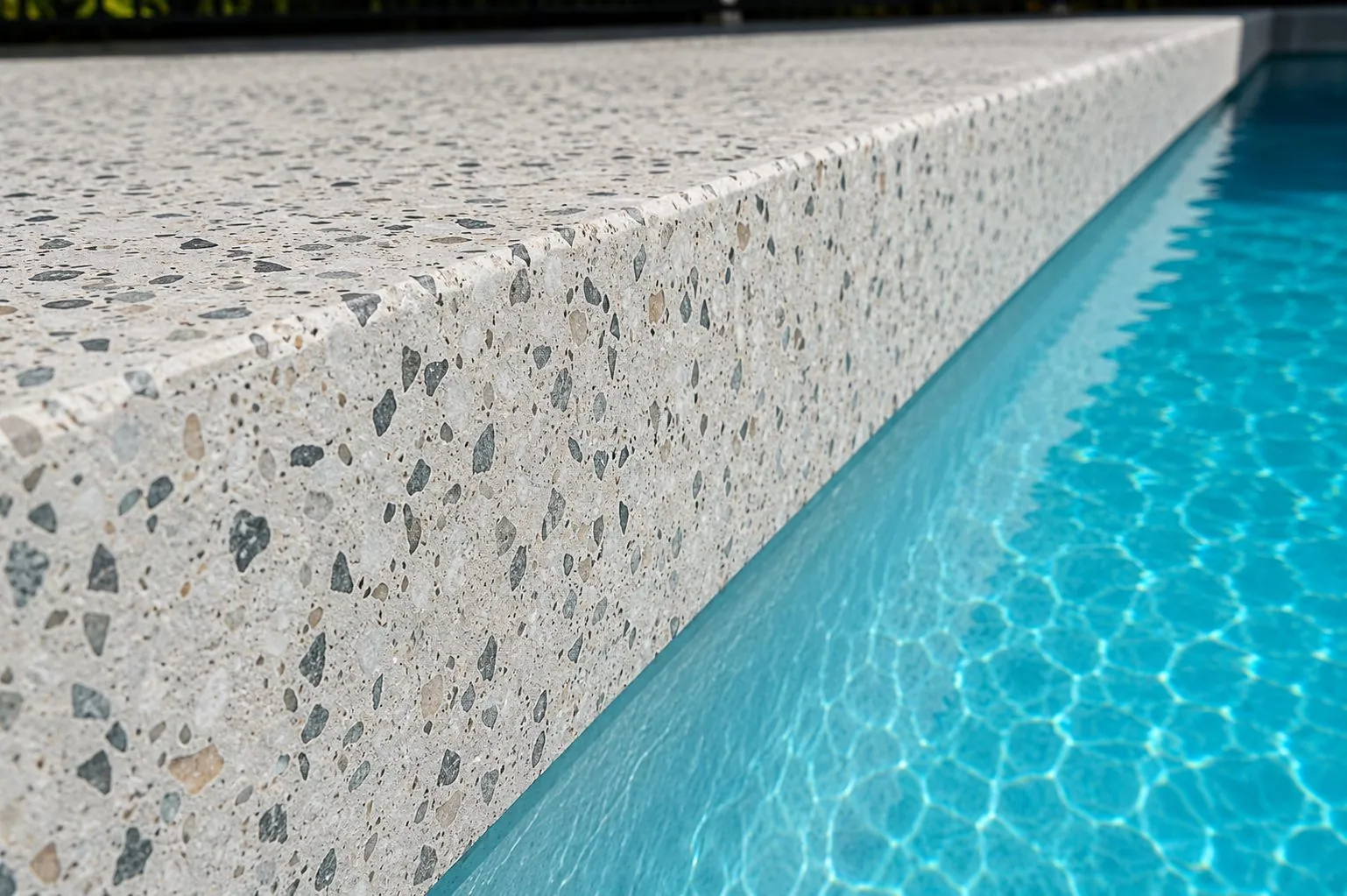 Close up of a seamless honed concrete pool edge with terrazzo style stone exposure in Brisbane