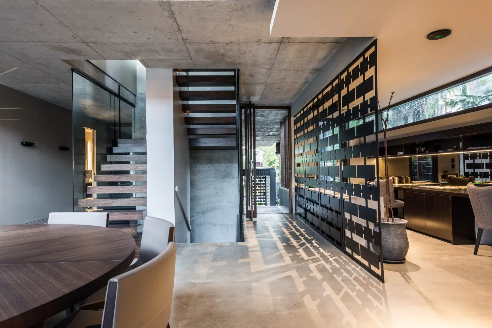 Architectural living space with a low-sheen polished concrete floor and floating timber stair