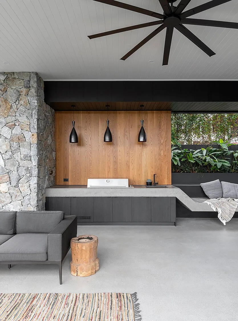 Living room with a stone feature wall and a natural matte concrete floor in Paddington
