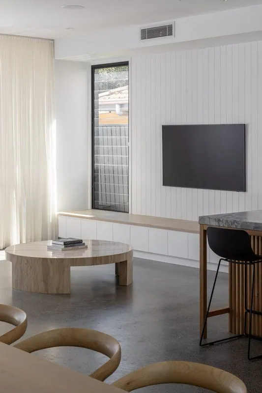 Living area with a round travertine table on a polished concrete floor at the Eclat Building home, Hendra