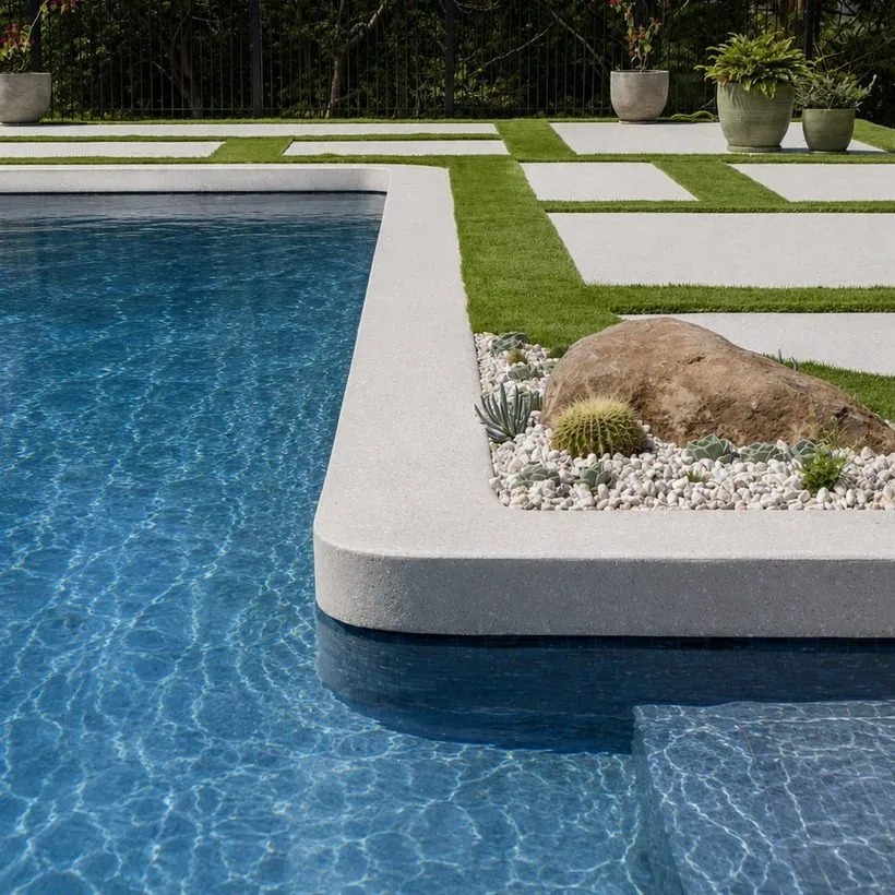 Honed concrete pool surround and coping by a backyard pool