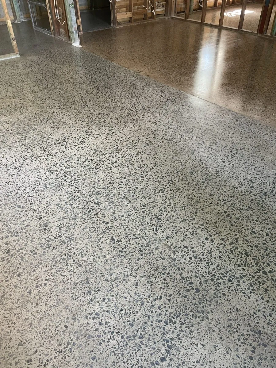 Hybrid polished concrete floor with exposed dark river-pebble aggregate in a Brisbane home by OzGrind
