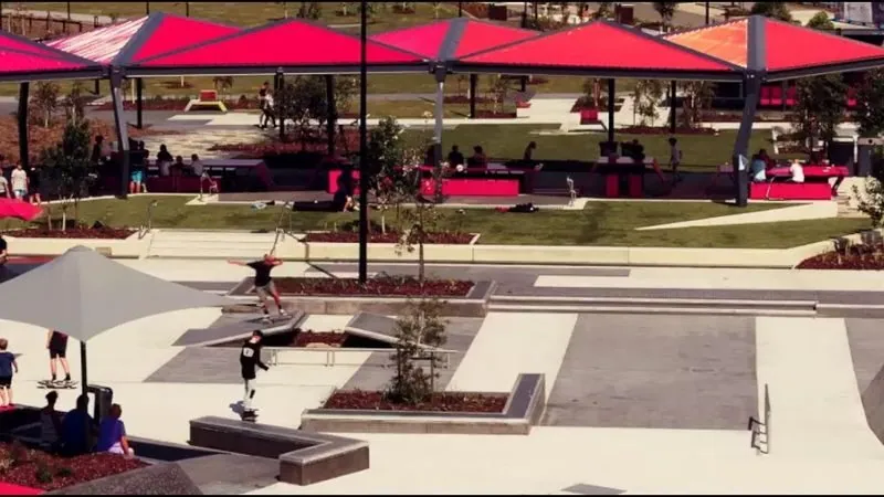 Honed concrete plaza under red shade sails at dusk, Baringa Town Centre outdoor polished concrete