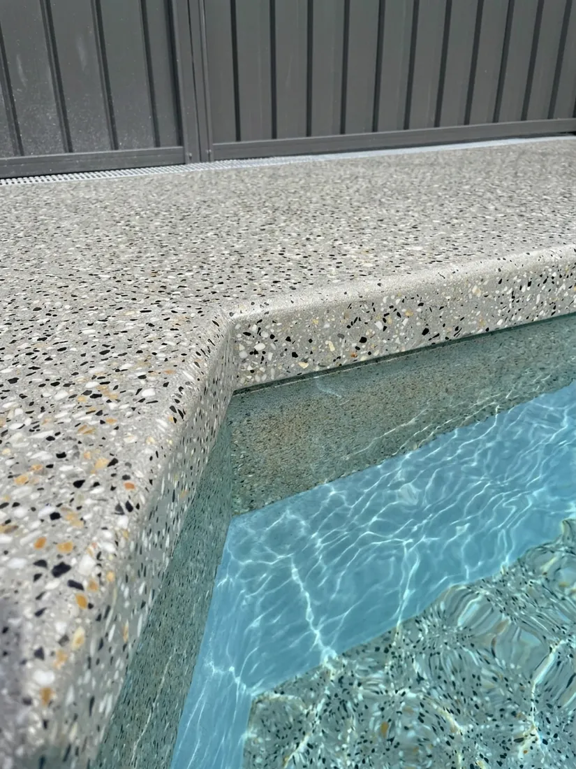 Seamless honed concrete pool coping and edge with full stone exposure at the waterline