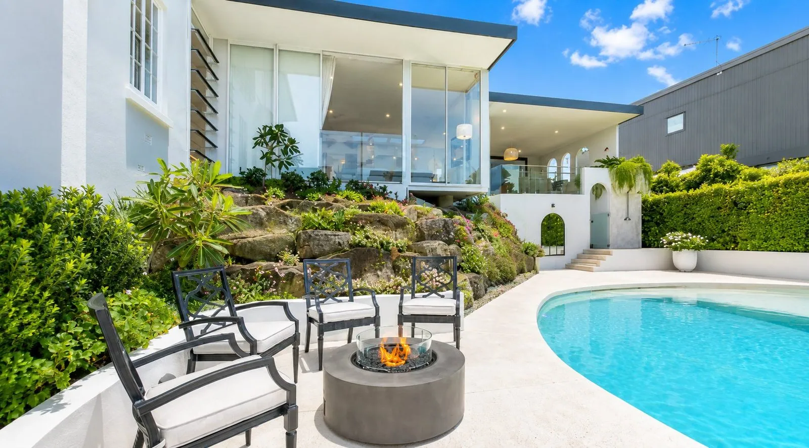 Honed concrete pool surround with a fire pit lounge area at a Brisbane home