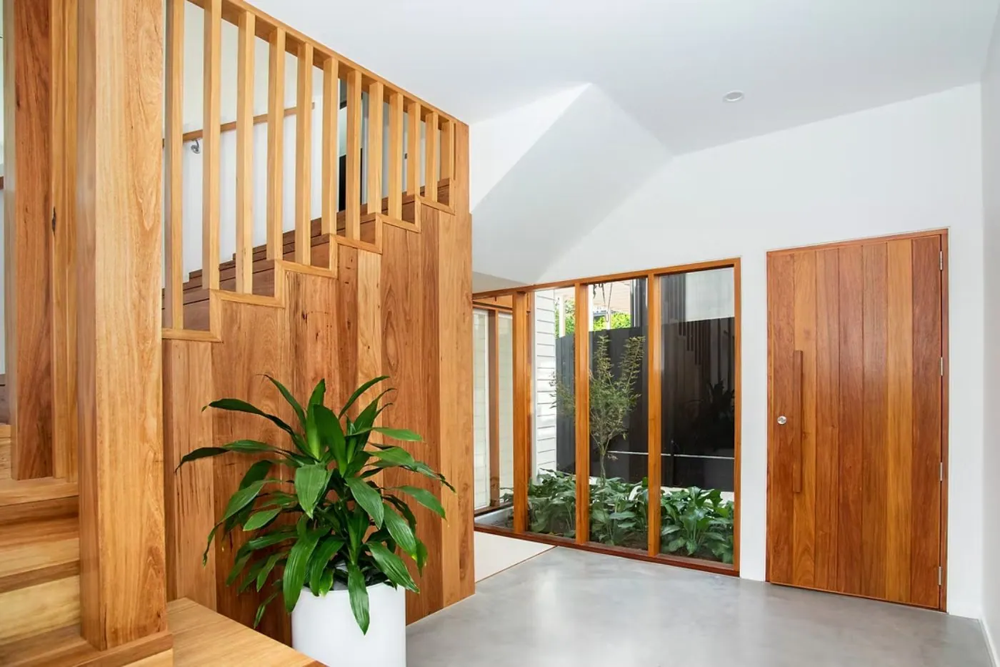 Microcement concrete overlay floor in a Brisbane home entry with timber staircase