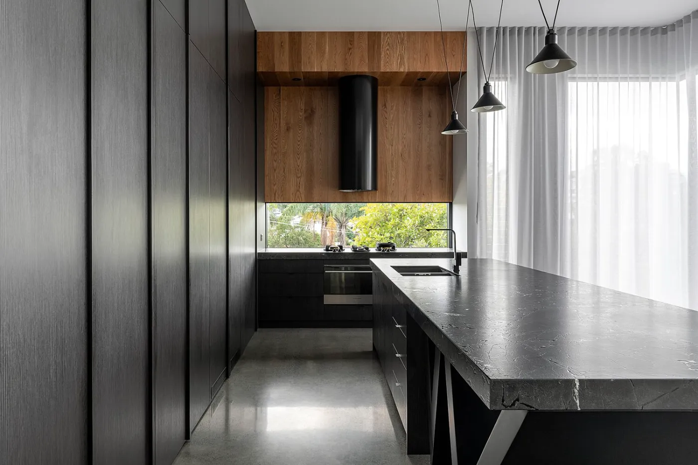 Mechanically polished concrete floor with a nil stone exposure high gloss finish in a dark timber and stone kitchen Brisbane