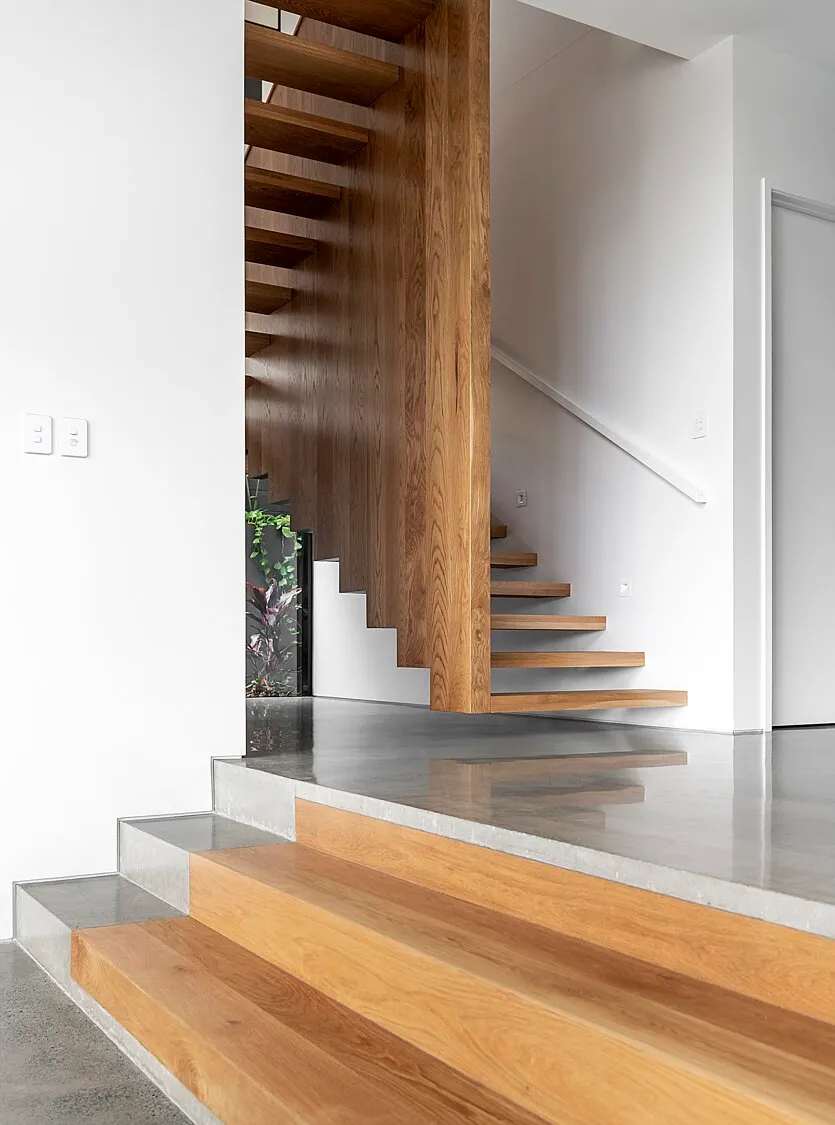 Mechanically polished concrete floor with a nil stone exposure high gloss finish by a timber staircase Brisbane