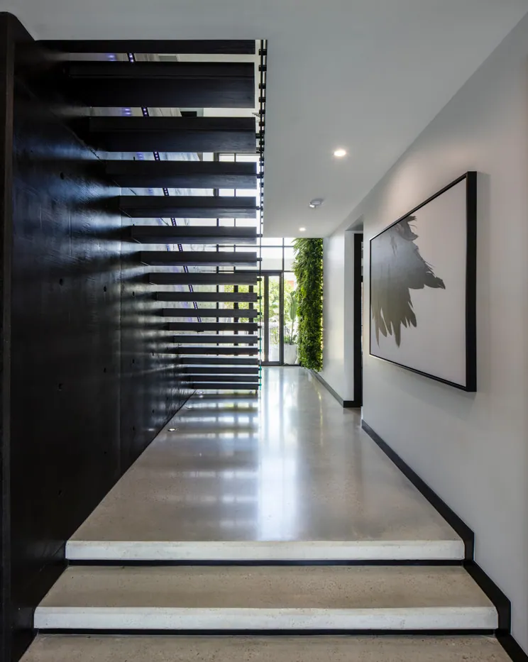 High gloss polished concrete floor and floating timber staircase in an architect designed Brisbane home