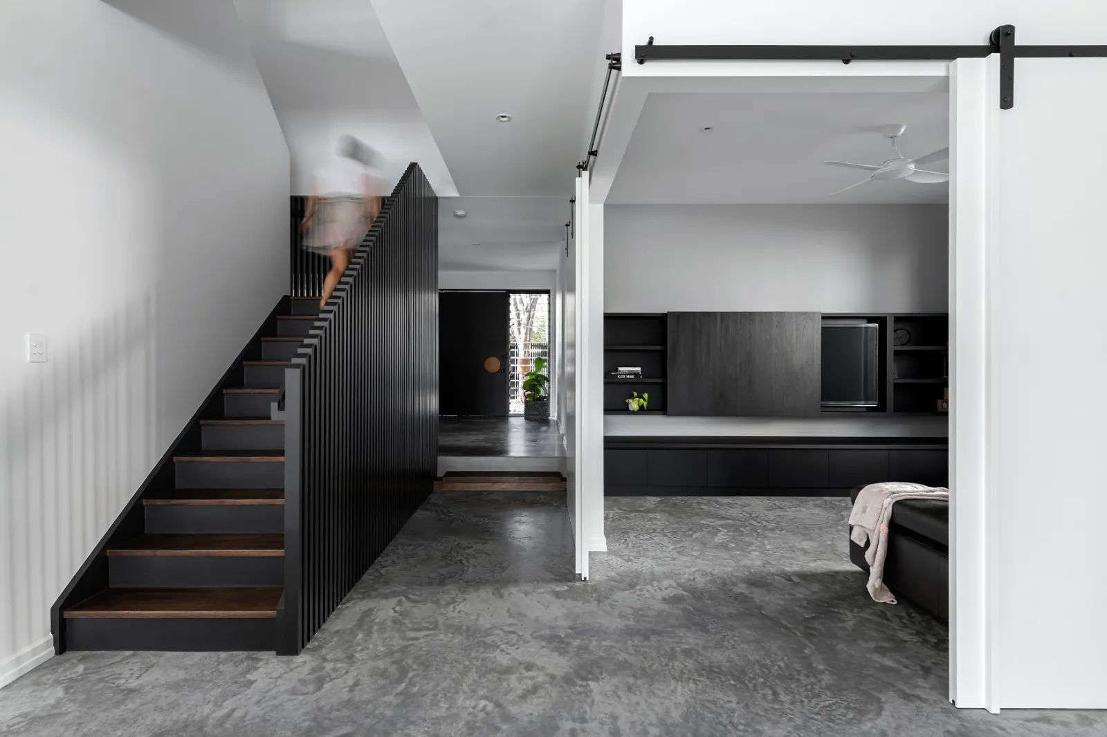 Indoor polished concrete floor in a Brisbane home with black timber staircase